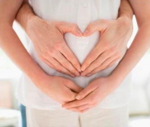 Husband forming heart-shape on pregnant wifes stomach